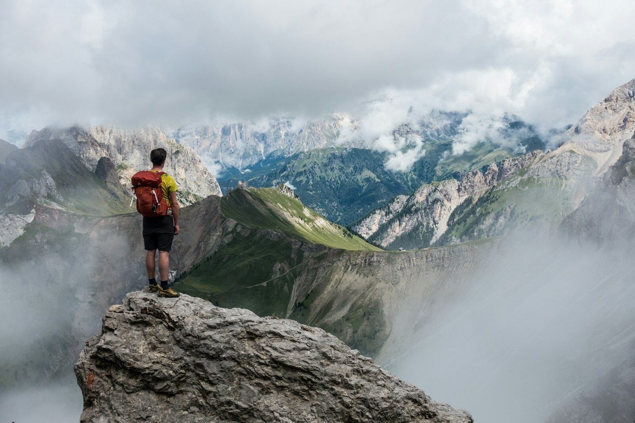 Escursionista in cima a una cresta alpina, sguardo verso le montagne — il Percorso come scalata